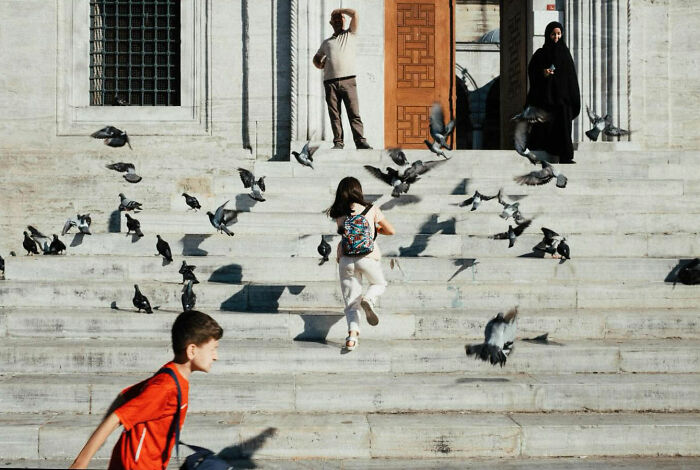 Children and adults interacting with pigeons on stone steps, showcasing the real candid side of life in Turkey.
