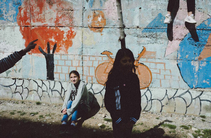 Children sitting and standing by a colorful graffiti wall, showcasing the real candid side of life in Turkey by Yusuf Aksoy.