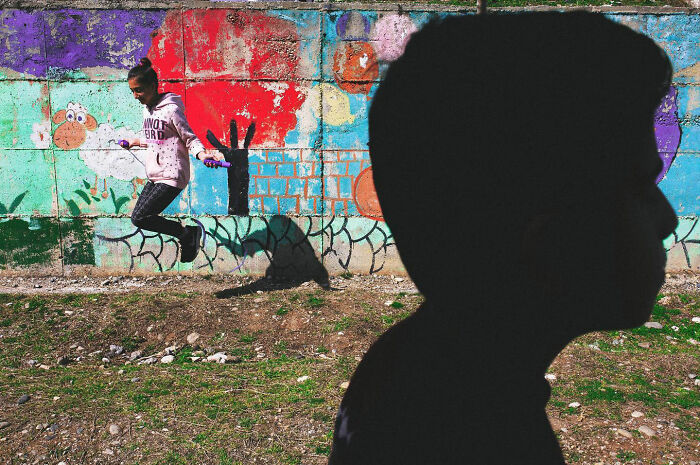 Child skipping rope near colorful wall mural, captured in a candid photo showcasing real life in Turkey by Yusuf Aksoy.