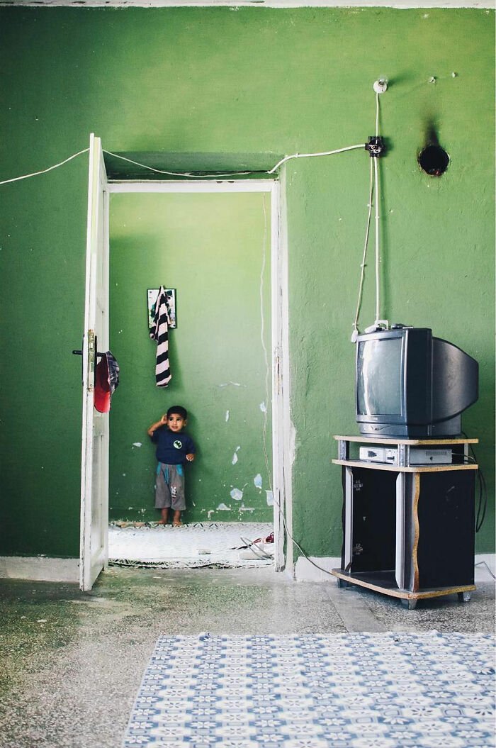 Child standing in a green-walled room with a vintage TV, capturing the real candid side of life in Turkey.