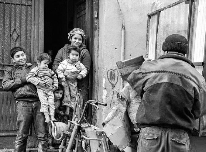 Black and white photo showing a candid moment of daily life with a family and a man collecting wood in Turkey.