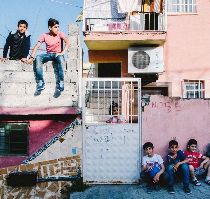 Boys sitting and playing outside colorful buildings, capturing the real, candid side of life in Turkey.