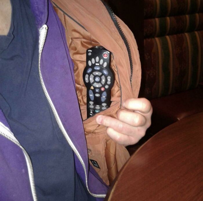 Person wearing a purple jacket holding a remote control tucked inside the jacket pocket, funny parents moment captured.