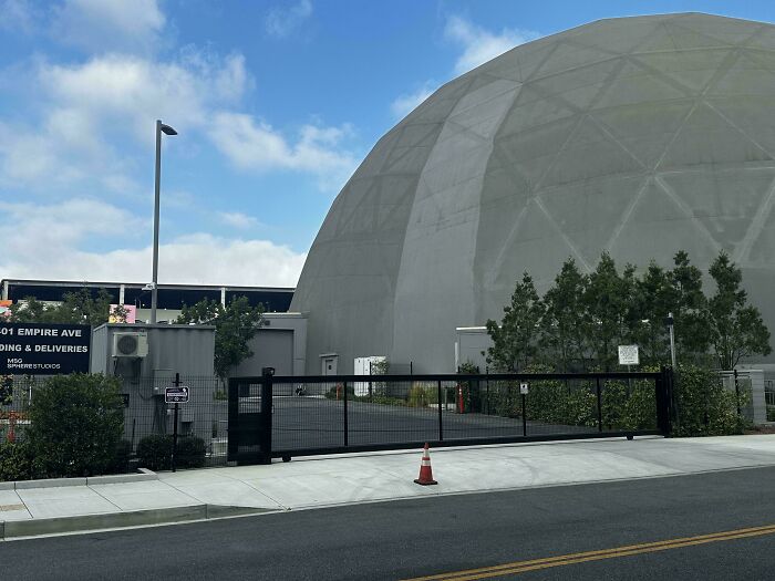 Large geodesic dome behind a gated entrance at an industrial area, capturing something moderately interesting to share.