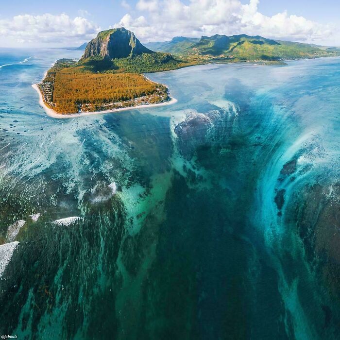 Aerial view of a beautiful island with clear blue waters, featuring an extremely large and picturesque landscape.