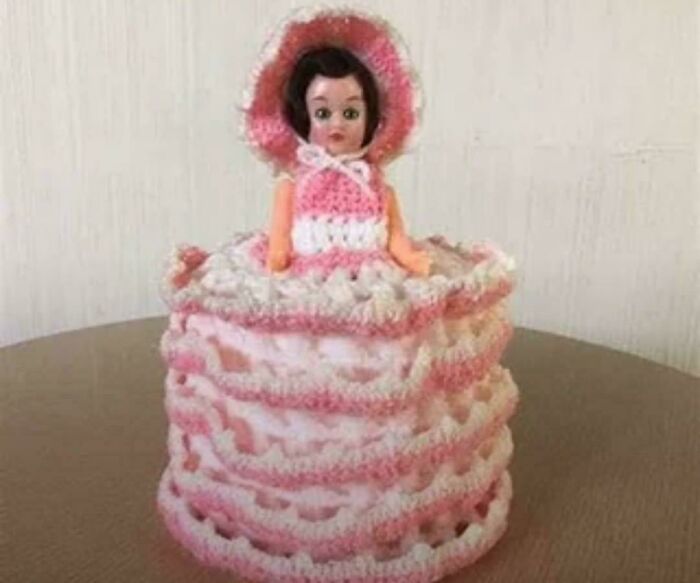 Vintage doll wearing a pink and white crocheted dress, a nostalgic item to make you feel old as heck.
