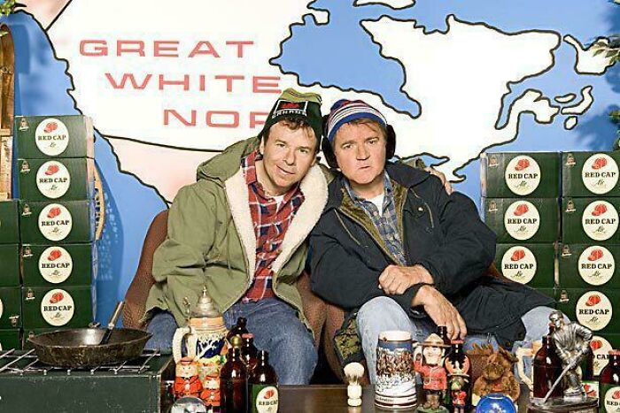 Two men in vintage outdoor clothing surrounded by retro beer boxes and nostalgic memorabilia, evoking feel old posts.
