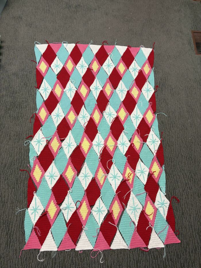 Colorful diamond-patterned crochet blanket in progress, showcasing intricate craftsmanship and creativity in crocheting projects.