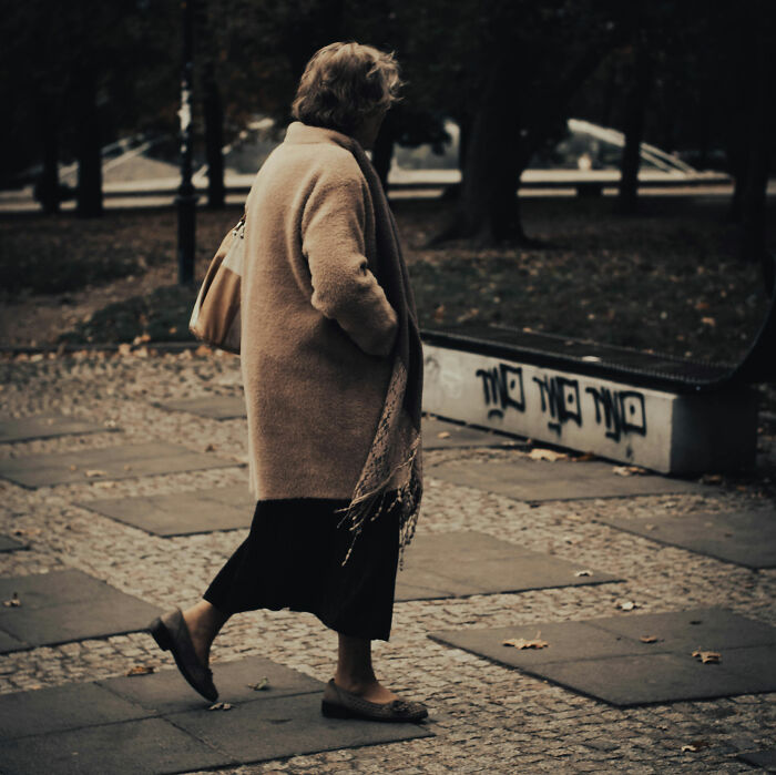 Elderly woman walking alone in a park, illustrating concerns about being knocked down by a neighbor&rsquo;s dog and self-protection.