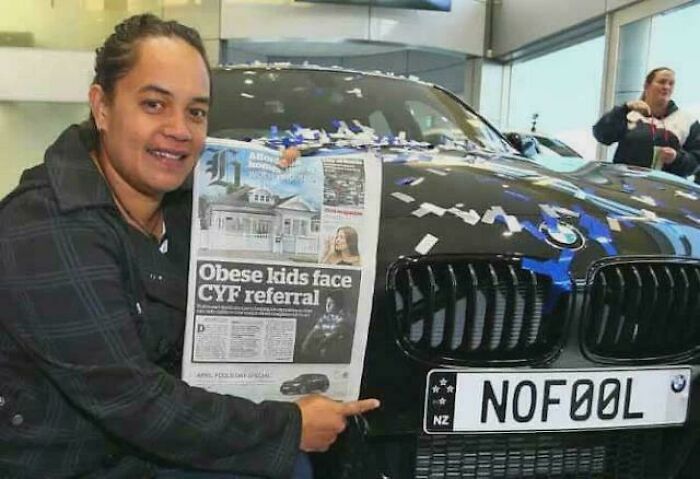 Person smiling beside a car with a custom NOFOOL license plate, symbolizing heartwarming stories to cleanse negativity.