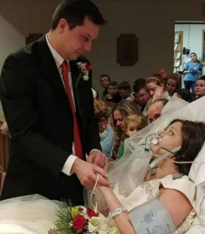 Groom holding hands with bride in hospital bed, capturing a heartwarming story of love and hope against all odds.