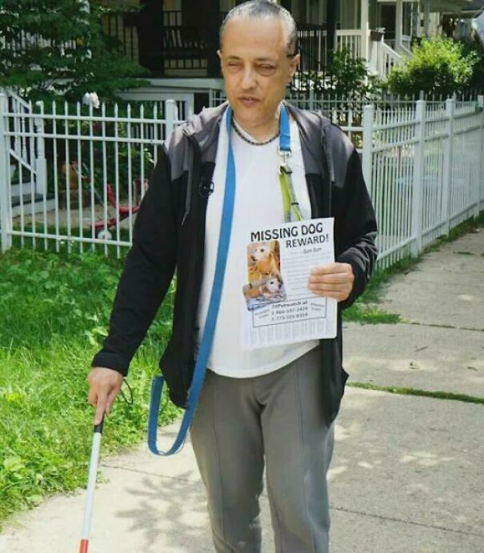 Man holding missing dog flyer while walking on sidewalk with cane, heartwarming stories to cleanse negativity.