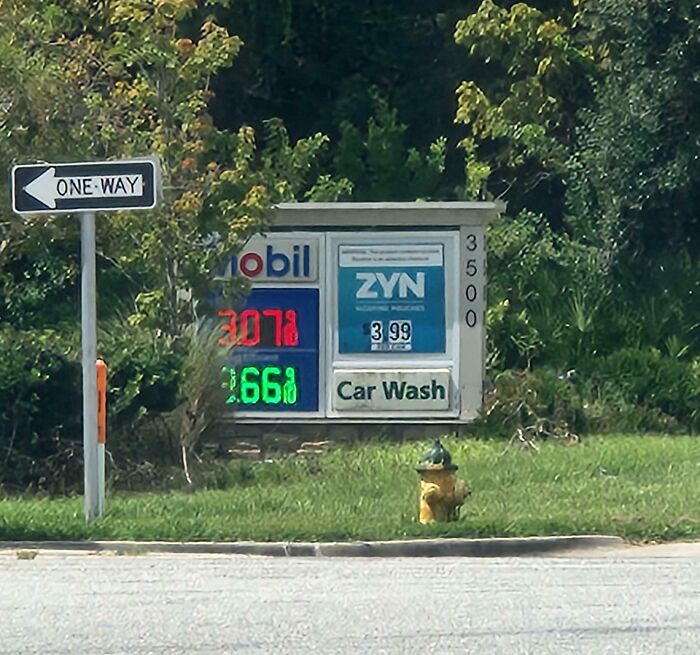 Gas station price sign showing high fuel costs and a one-way street sign, reflecting a dystopian nightmare scene.