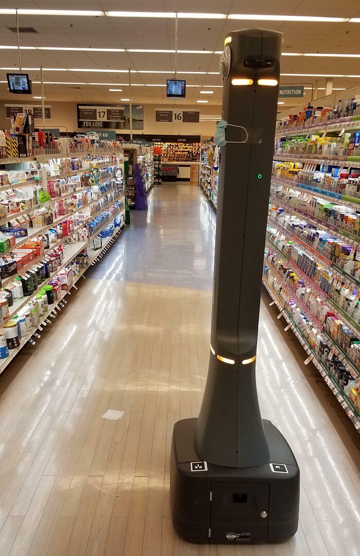 Autonomous security robot patrolling a grocery store aisle, a real-life dystopian scene in the US retail environment.