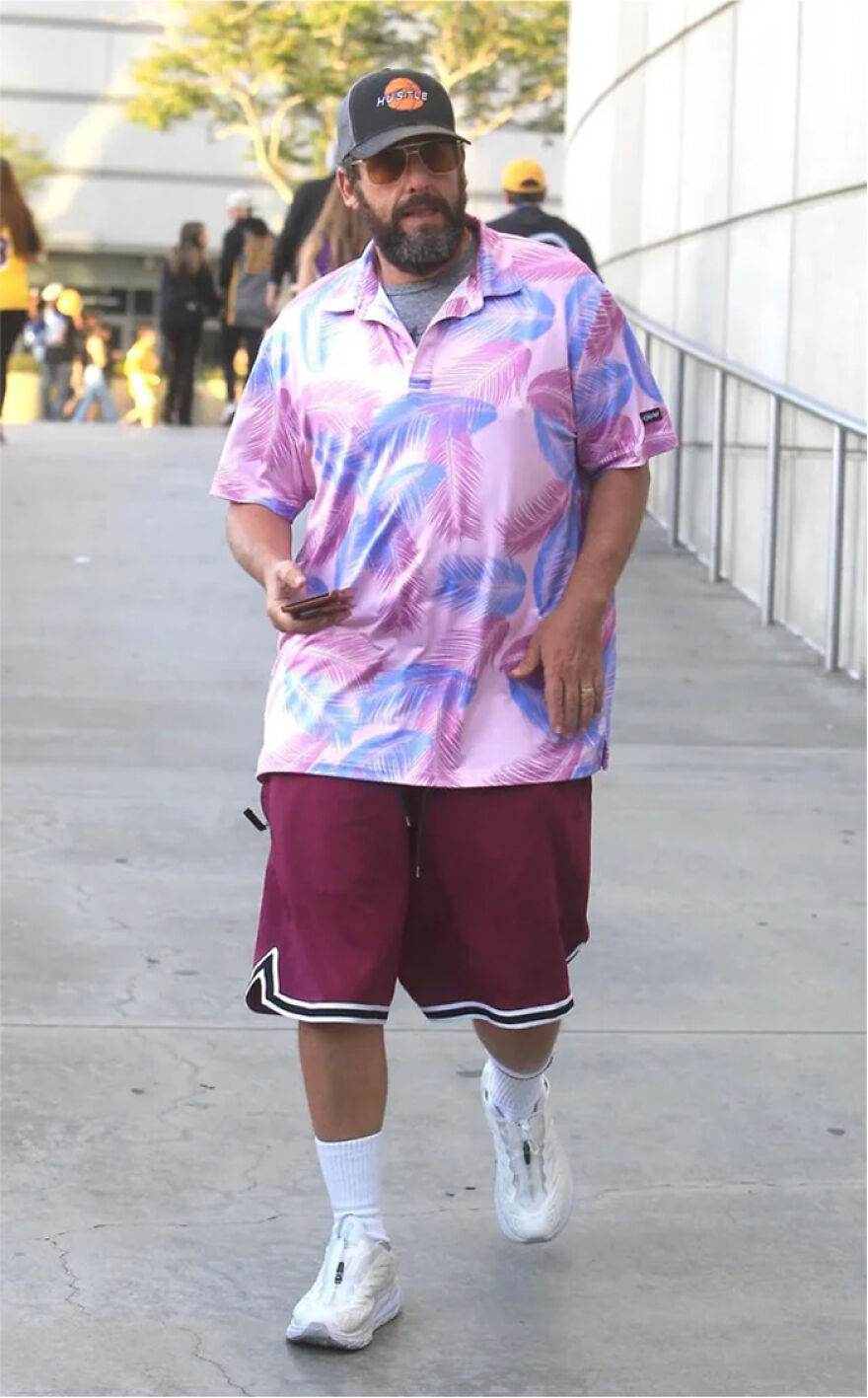 Adam Sandler wearing a colorful printed shirt and maroon shorts walking outdoors in a casual outfit for readers vote hall of fame.