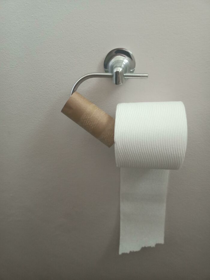 Toilet paper roll placed incorrectly over an empty cardboard roll on holder, showing an example of awful roommates behavior.
