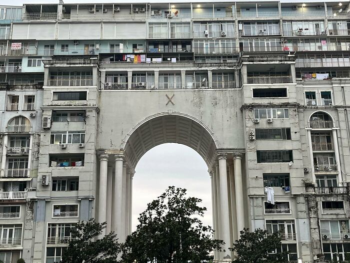 A large, weathered urban building with balconies and air conditioners, illustrating urban hell and societal decay.
