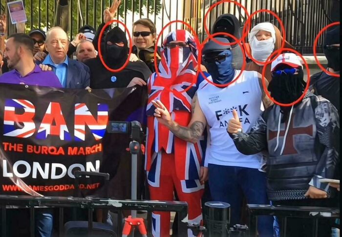 Group of masked protesters in London with a banner, some wearing UK flag clothing, part of there was an attempt fail pics.