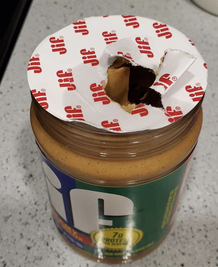 Partially opened peanut butter jar seal ripped unevenly, illustrating annoying habits of awful roommates people deal with.