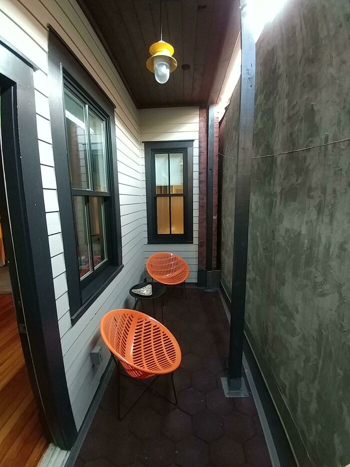 Narrow outdoor space with two orange chairs and a small table, illustrating unexpected purchases based on pictures.