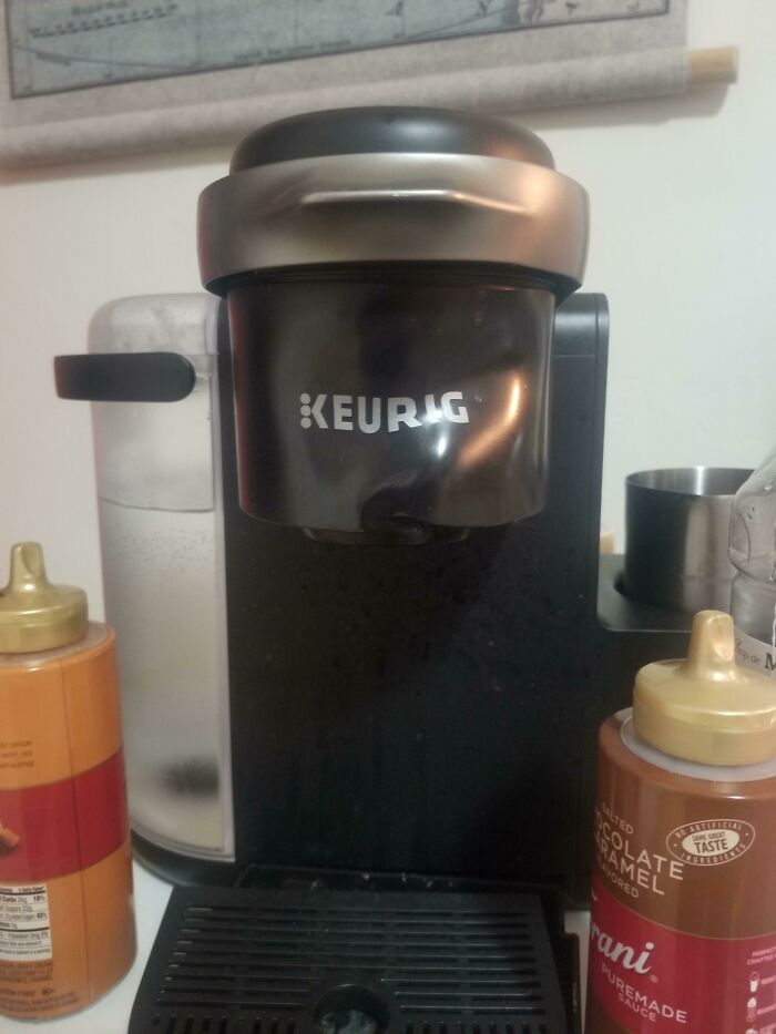 Keurig coffee maker surrounded by messy condiment bottles showing awful roommate kitchen clutter.