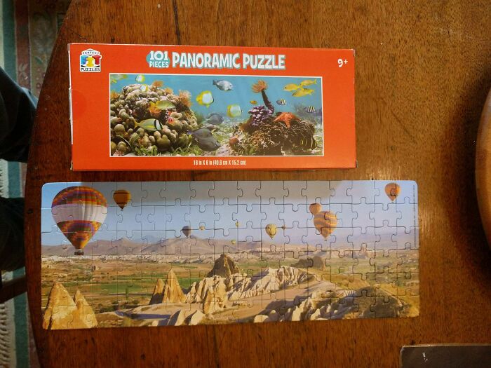 Panoramic puzzle box with underwater scene but completed puzzle shows a landscape with hot air balloons, illustrating purchase mismatch.