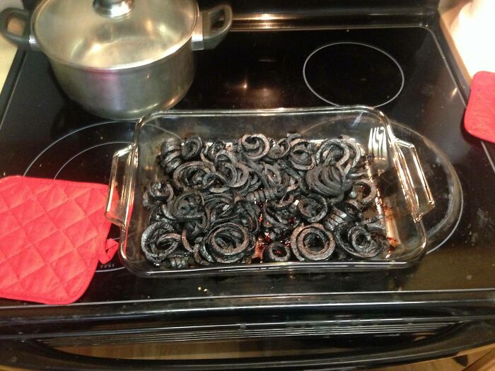 Burnt food leftovers in a glass baking dish on a stove, illustrating awful roommates and enraging kitchen situations.