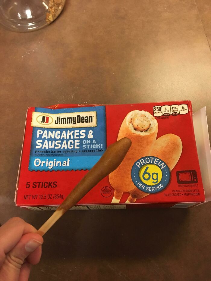 Hand holding an oddly shaped pancake and sausage stick purchased based on a picture that looks different from the product box.