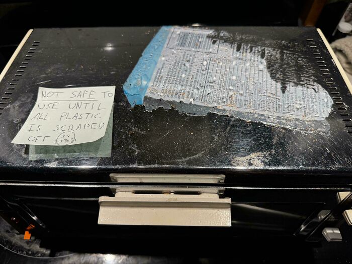Old dirty toaster oven with a warning note about plastic needing to be scraped off, showcasing awful roommates.