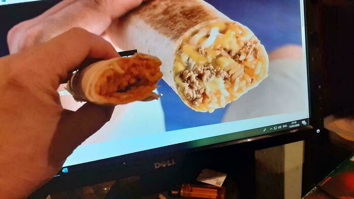 Hand holding a small, unappetizing burrito next to a screen showing a large, cheesy burrito, example of misleading purchases.