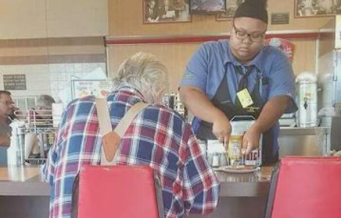 A restaurant worker serving an elderly customer, showcasing a heartwarming story of kindness and care.