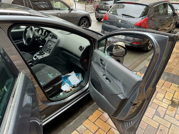 Car door smashed with broken glass on seat and floor, showing bad luck on vacation with vehicle damage incident.