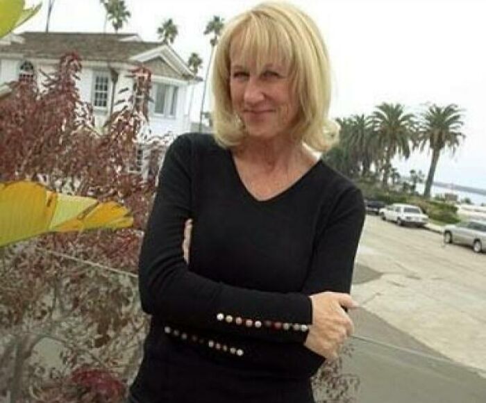 Woman smiling outdoors near plants and palm trees, evoking heartwarming stories to cleanse negativity from your feed.