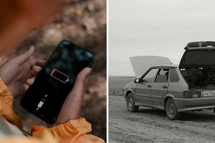 Person holding phone showing low battery icon, next to a broken-down car with open hood and trunk on a dirt road.