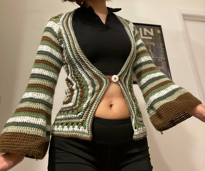 Person wearing a handmade striped crocheted cardigan with bell sleeves in neutral tones, showcasing crocheting skills.