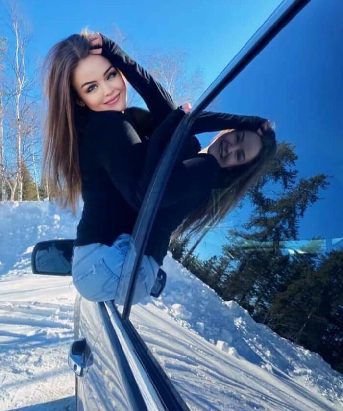 Woman posing on car window reflection outdoors in snow, illustrating social media filter fails and fake attempts on photos.