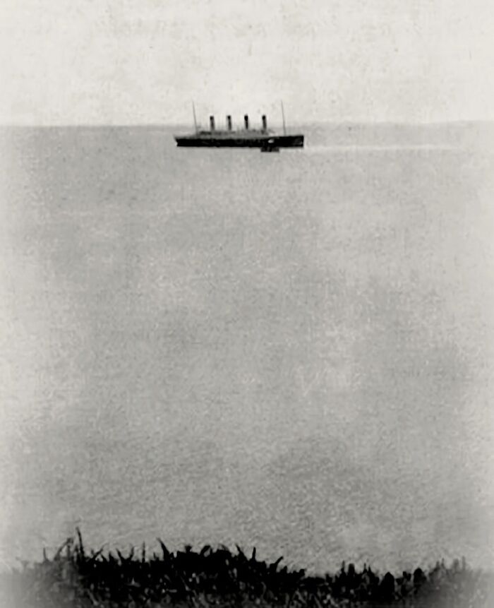 Rare historical photo of the Titanic floating in the distance above a mysterious fog over the ocean horizon.