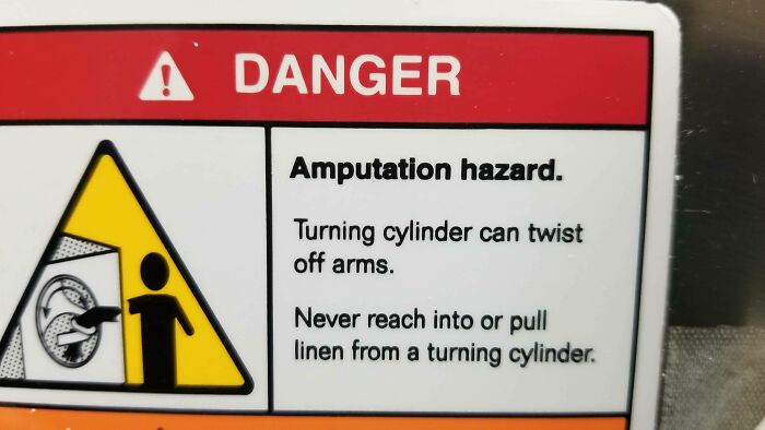 Warning sign showing amputation hazard from turning cylinder, highlighting dangerous work conditions in jobs that should pay more.