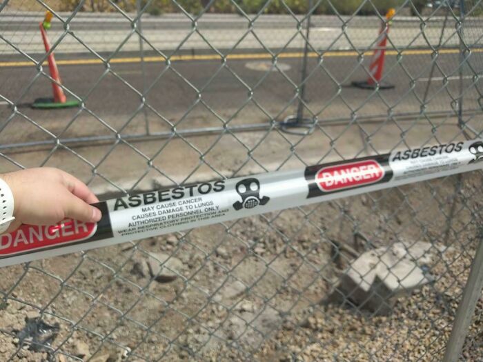 Danger asbestos warning tape on construction fence showing hazardous job site that should pay more based on workers' unsettling photos