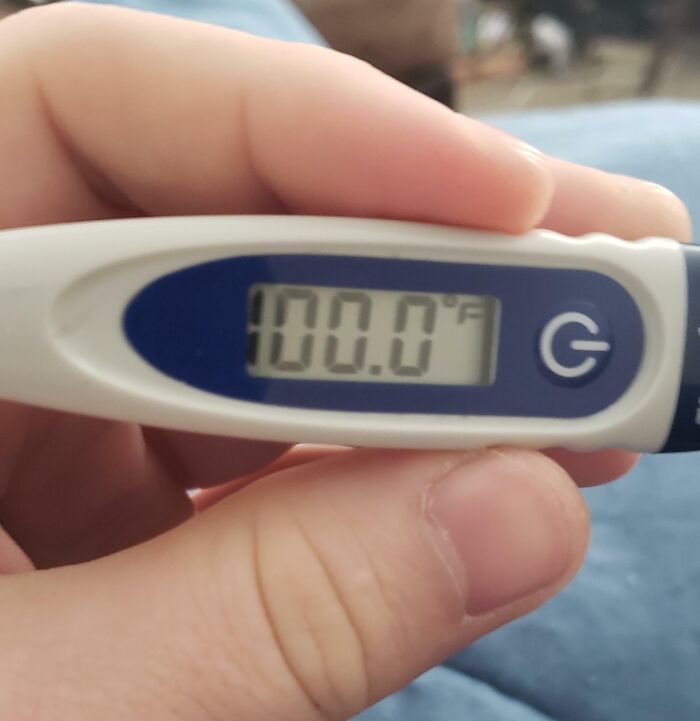 Close-up of hand holding a thermometer showing 100.0°F, illustrating reasons why people hate their boss.