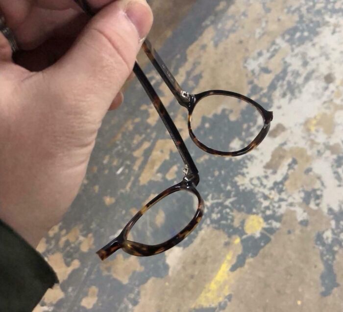 Hand holding broken eyeglasses with c*****d lens, illustrating frustrations people share about why they hate their boss.