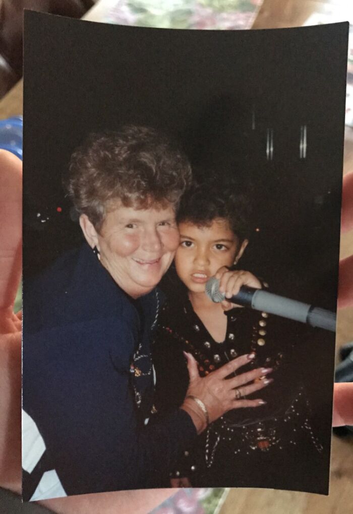 Vintage vacation photo of a child holding a microphone next to a smiling elderly woman on a nostalgic trip.