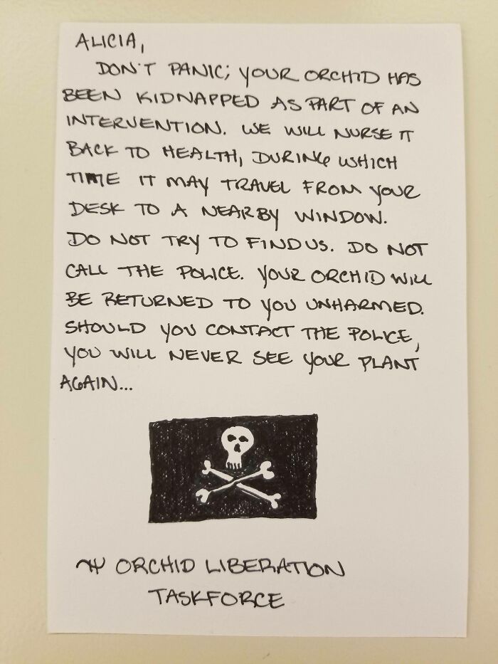 Passive-aggressive note from coworker threatening orchid kidnapping signed by Orchid Liberation Taskforce with skull and crossbones drawing.