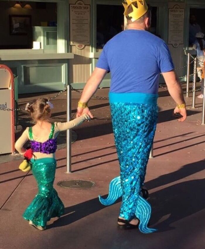 Father and daughter dressed as matching mermaids holding hands, showcasing one of the funniest parents ever moments.
