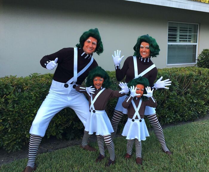 Family dressed in funny costumes with green wigs and striped stockings, showing the funniest parents and kids posing outdoors.