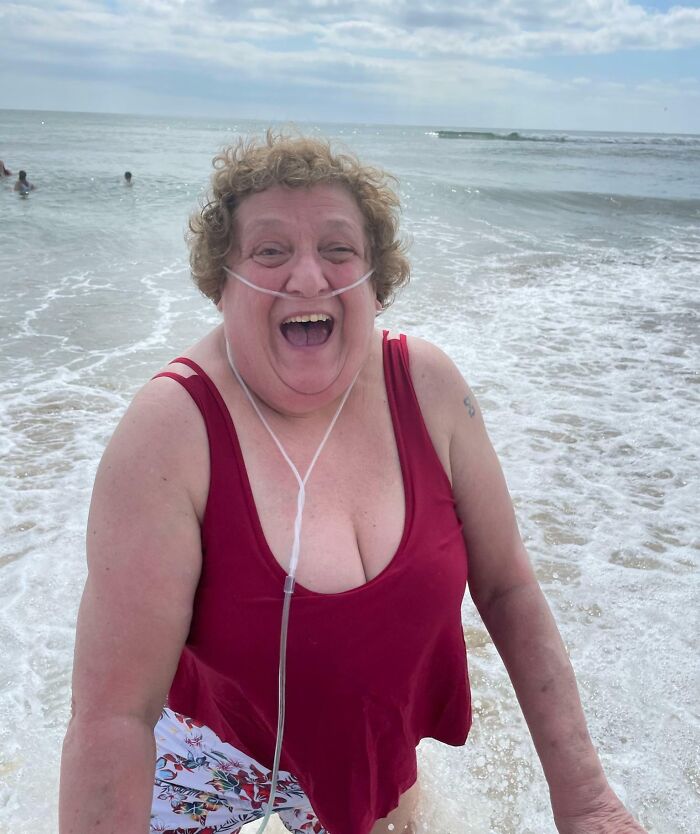 Laughing mom with oxygen tube enjoying the beach, one of the happiness-inducing pics of moms being their amazing wholesome selves