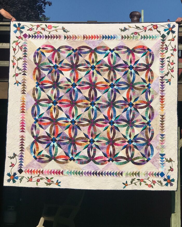 Colcha colorida con diseño entrelazado y bordes florales, creando un ambiente acogedor y creativo para las madres.