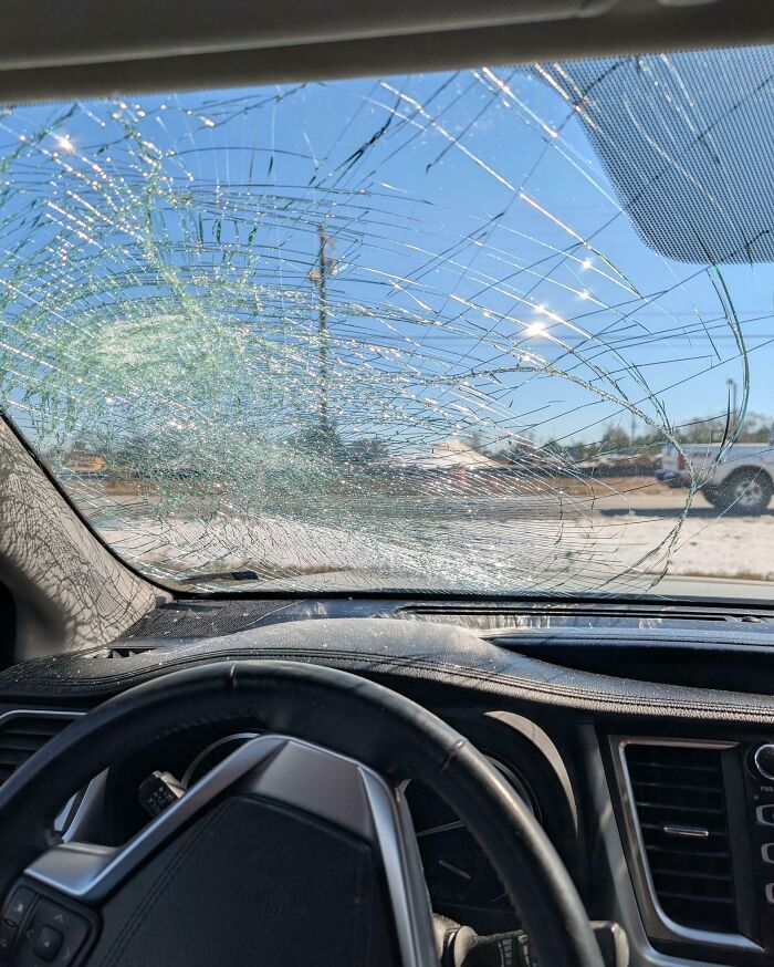 View from inside a car showing a shattered windshield, illustrating worst luck on vacation moments shared.