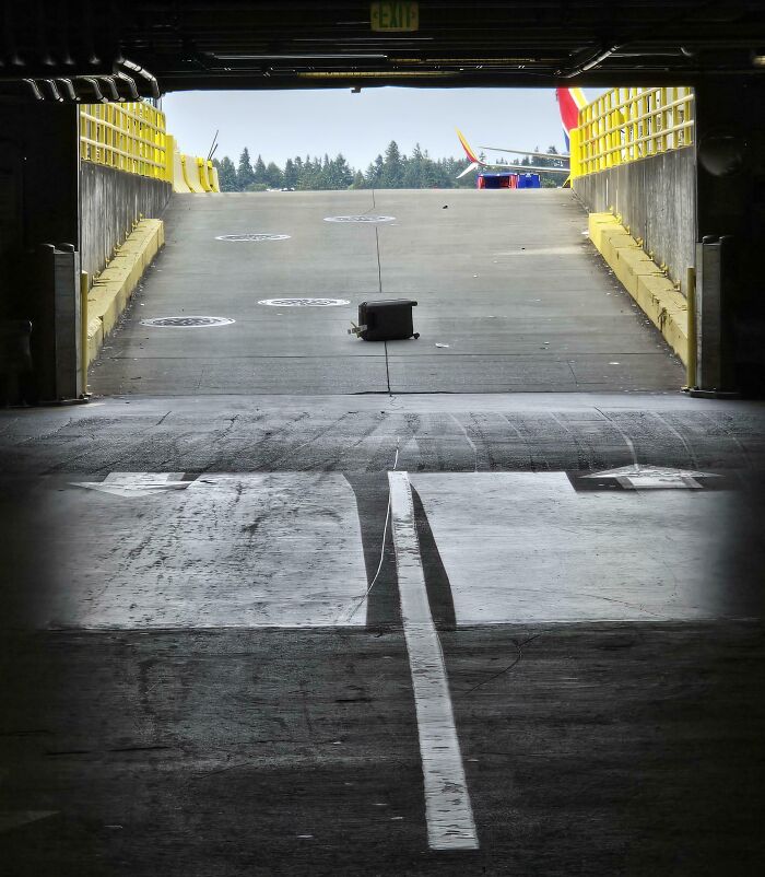 Abandoned suitcase blocking the exit ramp of a parking garage, illustrating worst luck on vacation mishaps.