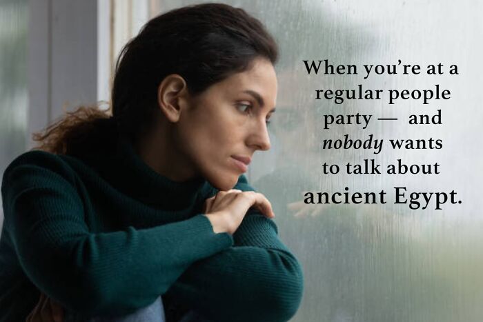 Woman in a dark sweater looking out a window with a meme about ancient Egypt and archaeology humor.